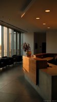 Modern office lobby interior with warm lighting, wooden reception desk, contemporary furniture and large windows for corporate business design.