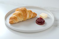 Fresh baked butter croissant served on white pat, minimalist breakfast composition on marble surface.