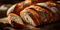 Freshly baked artisan bread loaves with golden crust sliced on wooden cutting board. Homemade bakery products for breakfast, cooking and food photography.