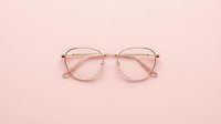 Pair of transparent rose gold eyeglasses with metal frame isolated on soft pink background, suitable for fashion, optical retail, and eyewear design projects.