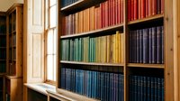 Colorful vintage books arranged by color on wooden library shelves creating rainbow pattern. Classic literature collection in traditional bookcase for education and reading.