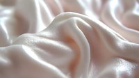 Luxurious pale pink satin fabric with soft folds and shimmering surface texture for fashion design, wedding decor, and elegant textile projects.