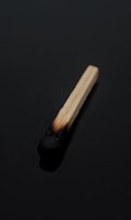 Burnt wooden matchstick with charred black tip on dark background symbolizing failure, burnout, exhaustion or end of resources concept.
