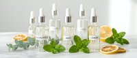 Natural skincare serum bottles with eucalyptus, mint and citrus ingredients on white marble surface for organic beauty and wellness products.