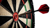 Red dart arrow hitting bullseye center of dartboard target showing precision accuracy and goal achievement concept for business success strategies.