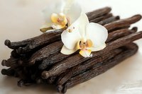 Aromatic vanilla pods with delicate orchid flowers on neutral background for culinary and spa themes.