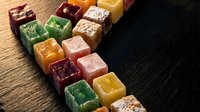 Colorful assorted fruit jellies and gummy candies arranged in rows on wooden surface for confectionery and sweet treat concepts.
