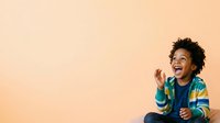 Young man with dark curly hair and medium brown skin tone, wearing a teal and yellow striped shirt over a navy top, smiling and gesturing expressively against a warm beige background. Suitable for lifestyle, education, and communication concepts.