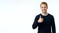 Young Caucasian male wearing dark navy long-sleeve shirt giving thumbs up gesture against white background, suitable for business, success, and approval concepts.