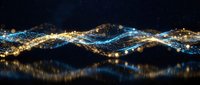 Glowing blue and gold particle waves flow across a dark background with bokeh light reflections, evoking digital energy and futuristic data flow.