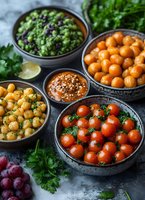 Colorful Mediterranean mezze spread with chickpeas, cherry tomatoes, olives and fresh herbs in rustic bowls for healthy cooking and dining concepts.