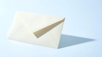 Cream paper envelope standing upright on light blue background, casting soft shadow, symbolizing mail, correspondence, and communication.