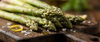 Fresh green asparagus spears with sea salt on rustic wooden cutting board, healthy organic vegetable ingredient for cooking and culinary preparations.