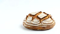 Freshly baked artisan sourdough bread loaf with golden crust and flour dusting isolated on white background for bakery and food design projects.