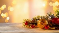 Festive Christmas decoration with golden and red ornaments on wooden surface against warm bokeh background for holiday greeting cards.
