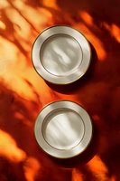 Empty white porcelain plates with gold trim on orange background with dramatic shadow play from window light, creating abstract patterns for food photography styling.