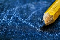 Sharp yellow wooden pencil tip on dark blue textured background with dramatic lighting and shallow depth of field, creating artistic composition for education concepts.