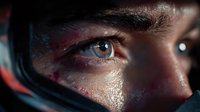 Close-up of intense blue eye visible through racing helmet visor, showing determination and focus of motorsport competitor in dramatic lighting.
