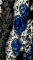Blue sapphire crystals embedded in white marble rock formation showing natural mineral geology and precious gemstone deposits in raw uncut state.