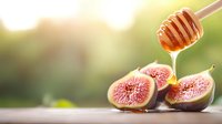 Fresh ripe figs cut in half with golden honey dripping from wooden dipper, natural bokeh background creates soft dreamy atmosphere for food styling.