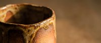 Handmade ceramic pottery cup with rustic brown glaze and natural earth tones, showcasing traditional craftsmanship and artisanal texture for home decor.