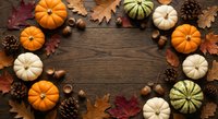 Autumn harvest frame with colorful pumpkins, pine cones, acorns and fall leaves arranged on rustic wooden background for seasonal decoration and thanksgiving.