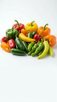 Fresh assorted peppers including red, yellow, orange, and green bell peppers with hot chili peppers on white background for culinary and food styling projects.