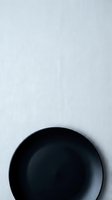 Black ceramic bowl on white textured background, minimalist tableware flat lay for kitchen and dining design projects.