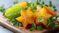 Fresh star fruit slices with lime and herbs on wooden board, tropical exotic carambola ready for healthy snacking, cooking and food photography projects.