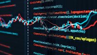 Programming code on computer screen with financial trading chart overlay showing market data analysis and software development for fintech applications.