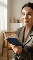 Middle-aged Caucasian businesswoman reading book in modern office interior, professional development and lifelong learning concept for corporate training.