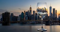 Empty wine glass with city skyline reflection at sunset, urban dining concept for restaurants and hospitality industry marketing materials.