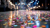 Colorful confetti scattered on wet city street at night with blurred bokeh lights creating festive atmosphere after celebration.
