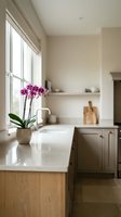 Bright modern kitchen with white marble countertop, magenta orchid in ceramic pot by window, wooden cabinetry, open shelving, and natural light for home design and interior decoration.