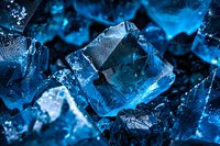 Macro shot of blue glowing crystal formation with sharp geometric shapes and facets against dark background, creating mystical mineral texture pattern.