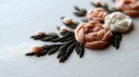 Delicate embroidered floral design with peach and cream roses on white fabric, featuring detailed green foliage and intricate needlework.