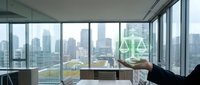 Modern law office with floor-to-ceiling windows overlooking city skyline, featuring scales of justice symbol, wooden desk, and professional workspace for legal services and corporate environments.