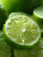 Fresh juicy lime slice with water drops on green background, extreme close up macro photography showing detailed citrus fruit texture and pulp segments.