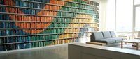 Modern home library interior with floor-to-ceiling bookshelves filled with colorful books creating rainbow gradient effect in contemporary living space.