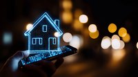 Glowing blue hologram house floating above smartphone screen with bokeh city lights background creates futuristic real estate technology concept.