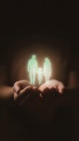 Glowing family silhouettes floating above protective cupped hands against dark background symbolizing life insurance coverage and financial security.