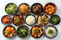 Traditional Korean side dishes banchan set with rice, kimchi, seaweed salad, marinated vegetables, and various spicy and savory accompaniments served in authentic black ceramic bowls.