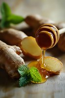 Fresh ginger root with honey dripping from wooden dipper, mint leaves on rustic wooden surface. Natural ingredients for healthy tea and immunity boost.