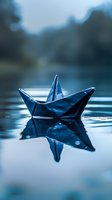Paper boat floating on calm water surface with reflection in moody blue tones, creating atmospheric minimalist scene for concepts of childhood, journey and hope.