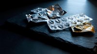 Empty medication blister packs on dark slate surface showing used pharmaceutical packaging for healthcare and medical waste concepts.