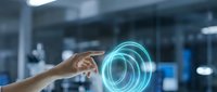 Hand touching glowing blue holographic circle interface in modern office environment showcasing futuristic technology and digital innovation concepts.