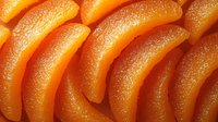 Candied orange slices arranged in rows showing crystallized sugar coating and translucent texture. Fresh citrus dessert garnish for culinary presentation.