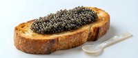 Toasted bread slice topped with luxurious caviar and served with mother-of-pearl spoon, isolated on white background for gourmet food styling and culinary design projects.