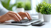 Professional woman hands typing on modern laptop keyboard at bright office desk with green plants creating productive workspace atmosphere for business work.