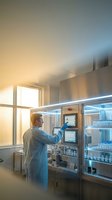 Male scientist in protective clothing operating advanced laboratory equipment in sterile research facility with modern technology and clean room environment.